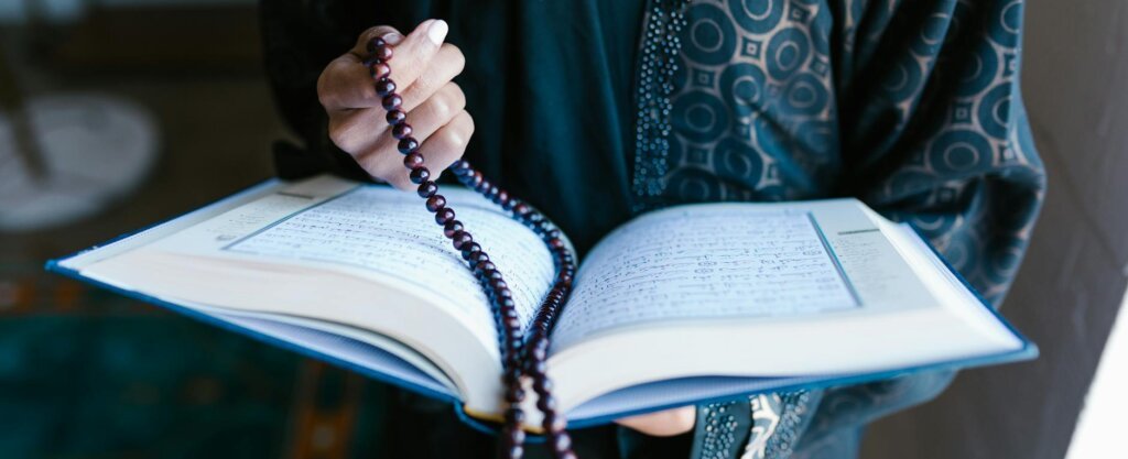 crop photo of woman holding a prayer beads and holy book